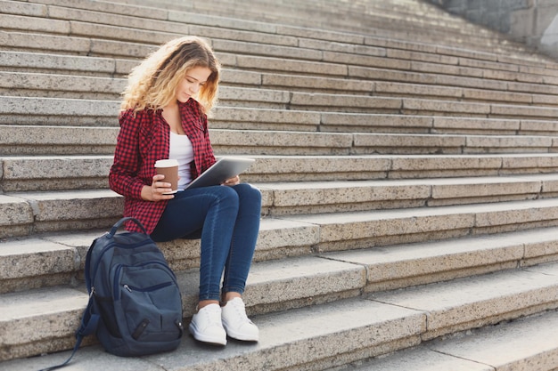 Linda aluna tomando café e trabalhando com laptop, preparando-se para exames ou descansando no campus universitário ao ar livre. tecnologia, educação e conceito de trabalho remoto, copie o espaço