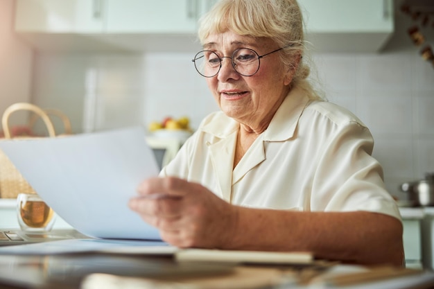 Linda anciana estudiando documentos en casa