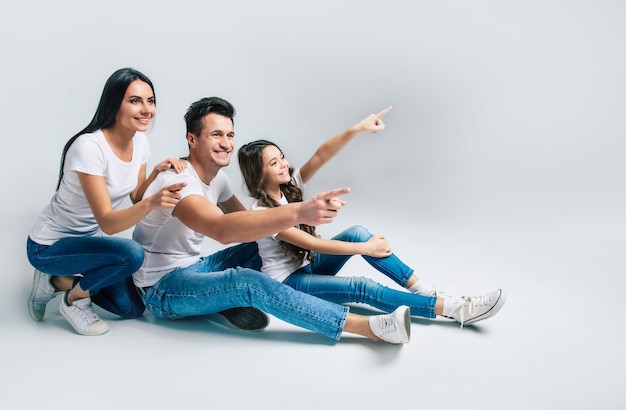 Linda, animada e a equipe engraçada da família está posando em uma camiseta branca, enquanto eles isolaram no fundo branco no estúdio.