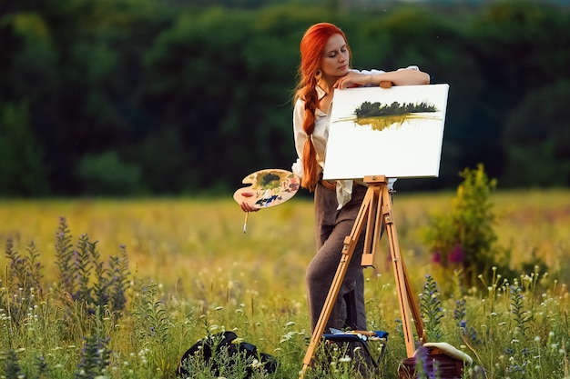 Foto linda artista feminina pintura ao pôr do sol na natureza