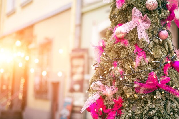 Linda árvore de natal com enfeites rosa no fundo da rua
