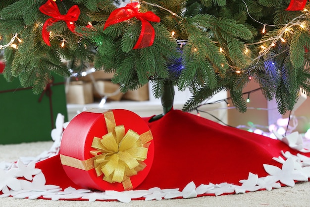 Linda árvore de Natal com saia e caixa de presente no quarto