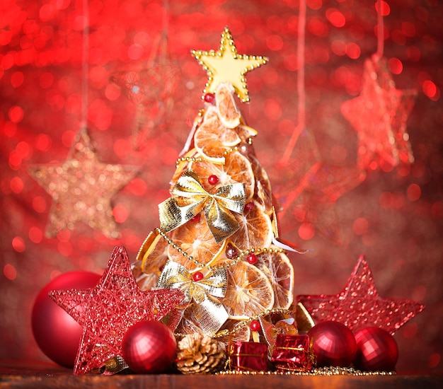 Linda árvore de natal de limões secos com decoração, sobre fundo vermelho