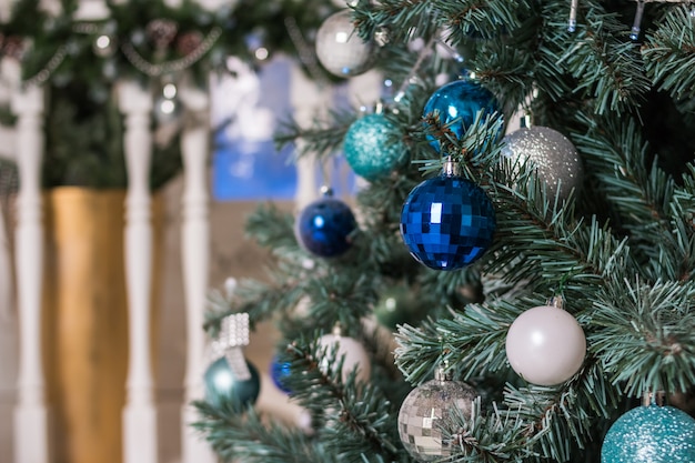 Linda árvore de Natal iluminada em uma sala de estar. Interior de sala de estar de luxo decorado com elegante árvore de Natal. Azul e prata enfeites de Natal, bolas, enfeites de Natal.