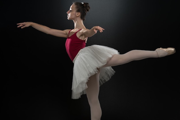 Linda bailarina feminina em um fundo preto bailarina está usando um tutu e sapatilhas de ponta