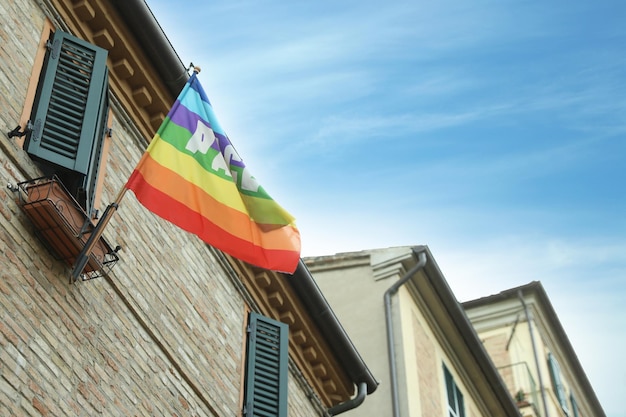 Linda bandeira da paz do arco-íris pendurada na parede do edifício vista de ângulo baixo