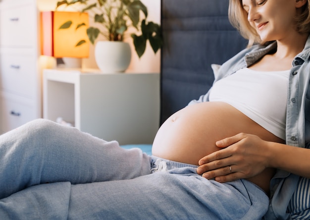 linda barriga de grávida de mulher deitada na cama futura mãe abraçando sua barriga e descansando