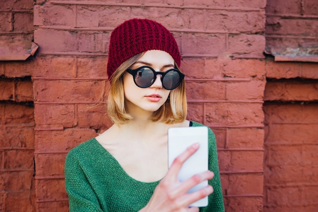 Linda y bonita mujer de moda y hipster milenaria con smartphone