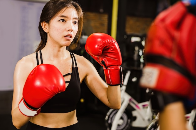 Linda boxer de mulher asiática praticando boxe em uma academia de ginástica.