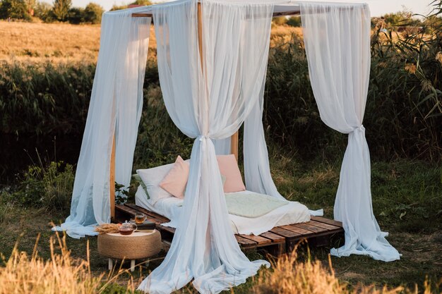 Foto linda cabana branca com cama grande e travesseiros na natureza