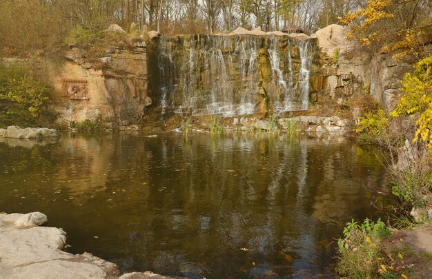 Foto linda cachoeira entre grandes rochas no parque sofievskiy da floresta de outono em uman ucrânia