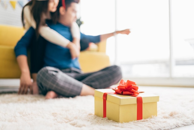 Linda caixa de presente e casal turva passando tempo de qualidade juntos durante as férias de Natal na sala de estar casal no fundo Ano novo ou conceito de aniversário Imagem com espaço de cópia