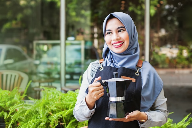 Linda camarera musulmana indonesia trayendo una cafetera