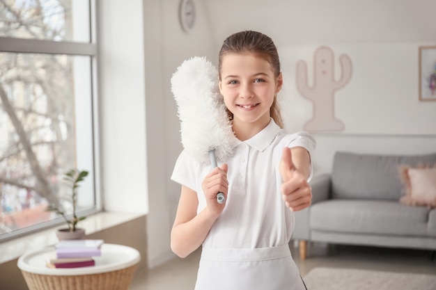 Linda camarera pequeña mostrando el pulgar hacia arriba en la habitación