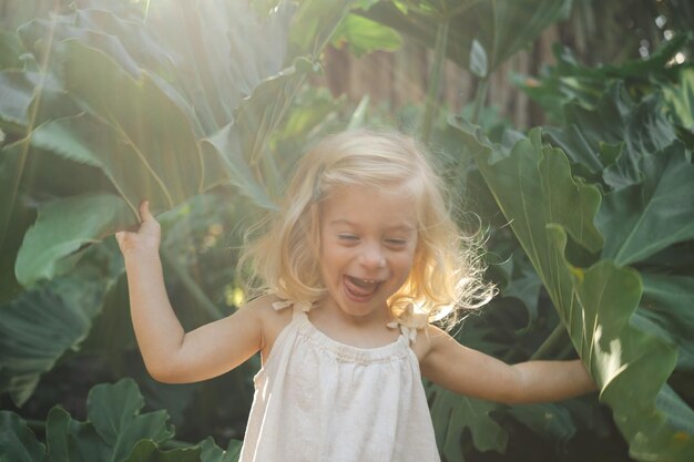 Foto linda caucasiana, muito feliz, sorridente, loira, menina de dois anos, criança, brincando entre a grande lea verde