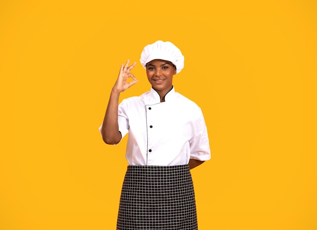 Linda chef negra usando chapéu mostrando gesto ok para a câmera
