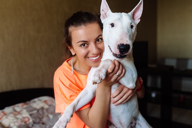 Linda chica acariciando a su bull terrier