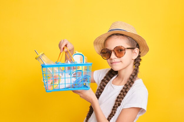 Linda chica adolescente con una cesta de la compra sobre un fondo amarillo de compras