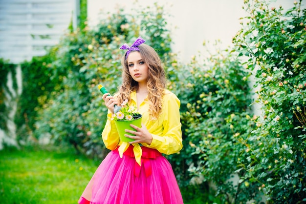 Linda chica adolescente feliz de 16 años con flores en el jardín de una maceta Primavera y verano Chica adolescente en el patio trasero del jardín de verano o en las tierras de cultivo Mujer plantando flores en una maceta