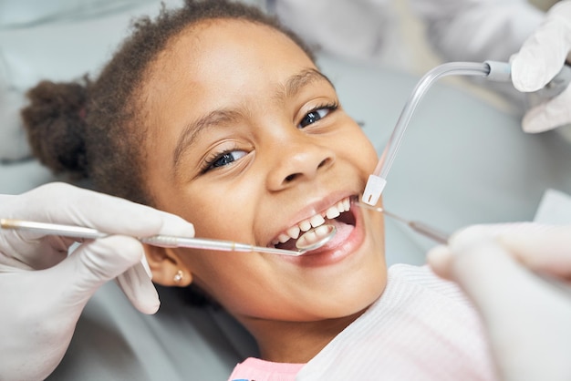 Linda chica africana durante el tratamiento dental en la clínica moderna