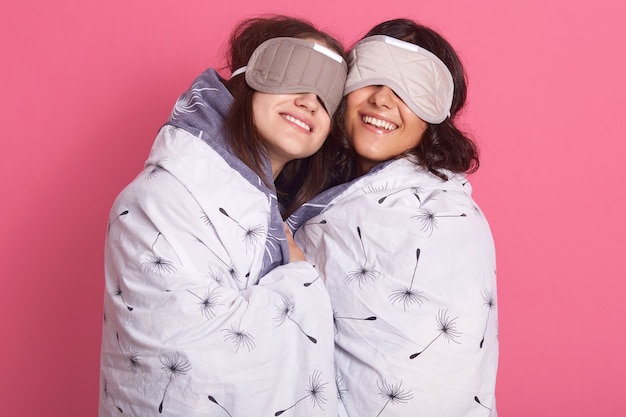 Linda chica amigas en traje de noche para una fiesta de pijamas sobre fondo rosa