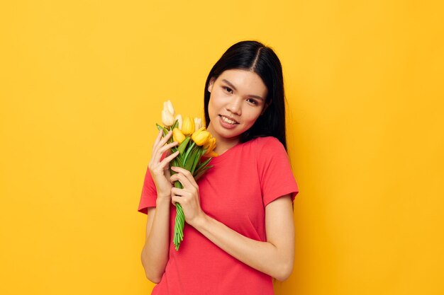 Linda chica asiática en camiseta roja con un ramo de flores