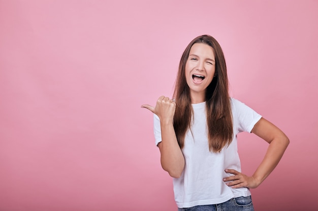 Linda chica atractiva fresca con camiseta muestra el pulgar al lado