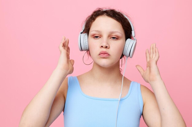 Linda chica con auriculares elegante ropa juvenil fondo rosa