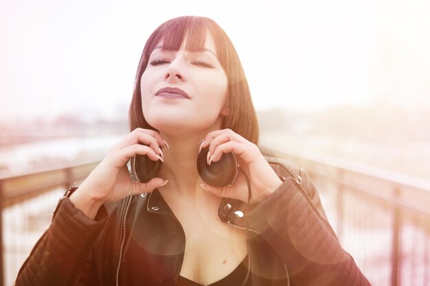 Linda chica en auriculares escuchando música al aire libre