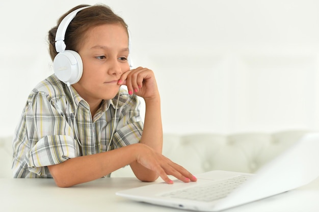 Linda chica en auriculares usando laptop en casa en el escritorio