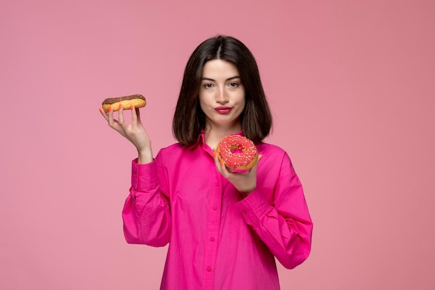 Linda chica bastante adorable chica en camisa rosa con lápiz labial rojo con dos deliciosos donuts