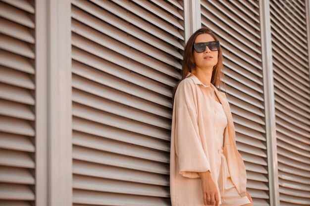 Una linda chica en beige y con gafas de sol posando