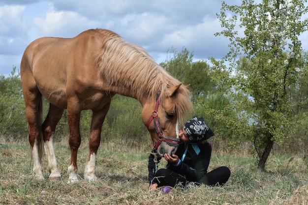 linda chica besando a su caballo en el fondo de la naturaleza