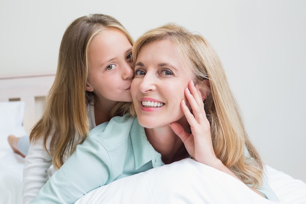 Linda chica besando a su madre sonriente