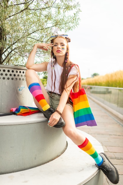 Linda chica bisexual con lgbt arco iris en la cara con accesorios coloridos.