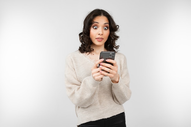 Linda chica con una blusa blanca con un teléfono inteligente en la mano con espacio de copia