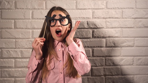 Linda chica en blusa rosa sosteniendo una pancarta con gafas negras en el fondo de la pared de ladrillo blanco