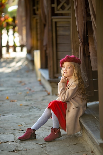 Linda chica de boina roja en un paseo en el otoño