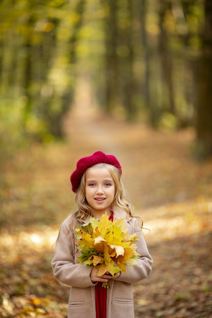 Linda chica de boina roja en un paseo en el otoño