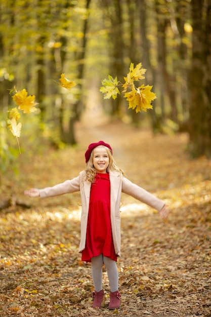 Linda chica de boina roja en un paseo en el otoño