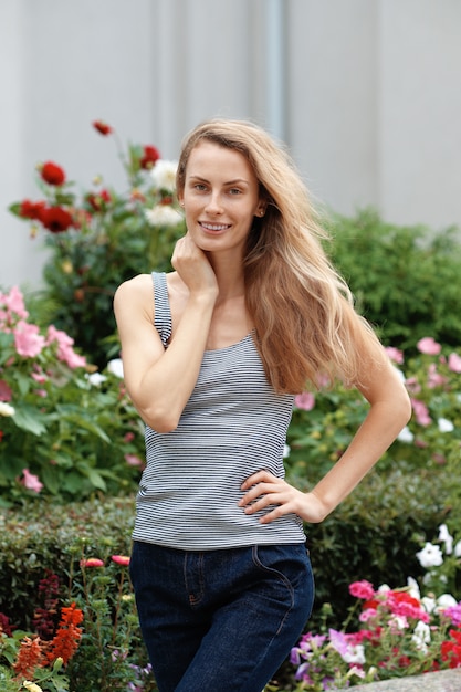 Linda chica caminando por el jardín de flores. Turista feliz con el viento en el pelo.