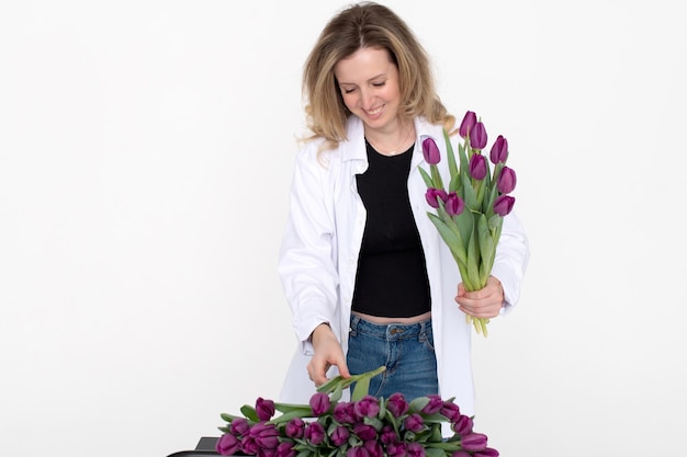 Linda chica en una camisa recoge un ramo de tulipanes morados para un regalo a su madre