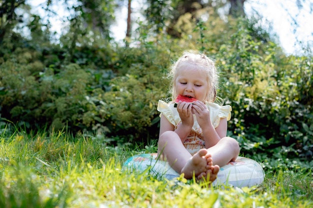 Linda chica caucásica comiendo sandía en el campo