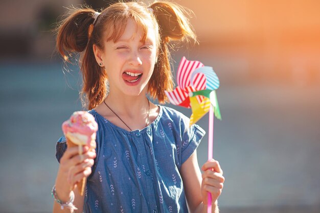 Linda chica comiendo helado en el fondo de verano al aire libre closeup retrato de adorable niña pelirroja comiendo helado