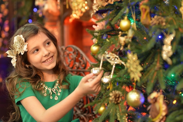 Linda chica decorando el árbol de Navidad en casa