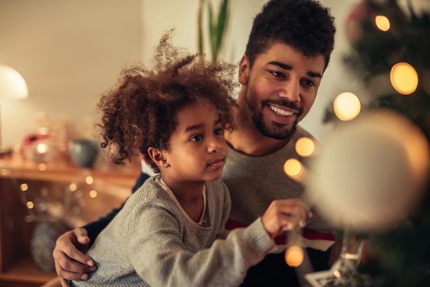 Linda chica decorando el árbol de Navidad con un papá