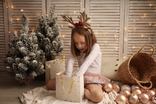 una linda chica con un disfraz de Año Nuevo saca una bola navideña de una bolsa de regalo