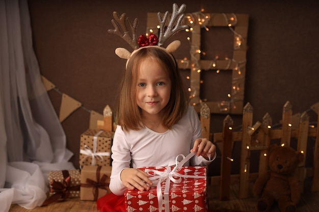 Una linda chica con un disfraz de Año Nuevo tiene un regalo de Año Nuevo en una caja