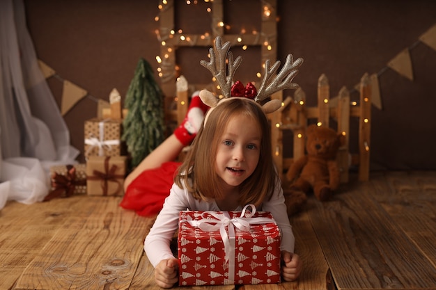 Una linda chica con un disfraz de Año Nuevo tiene un regalo de Año Nuevo en una caja