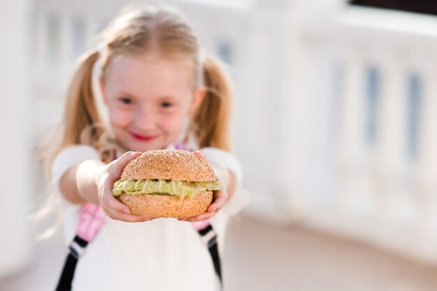 Linda chica divertida con hamburguesa con lechuga fresca